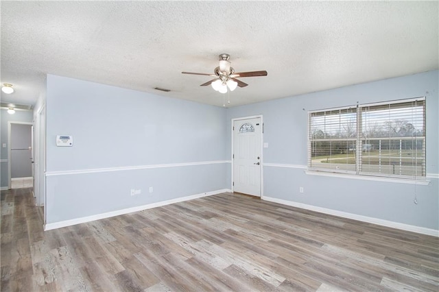 unfurnished room featuring light wood-type flooring, ceiling fan, baseboards, and a textured ceiling