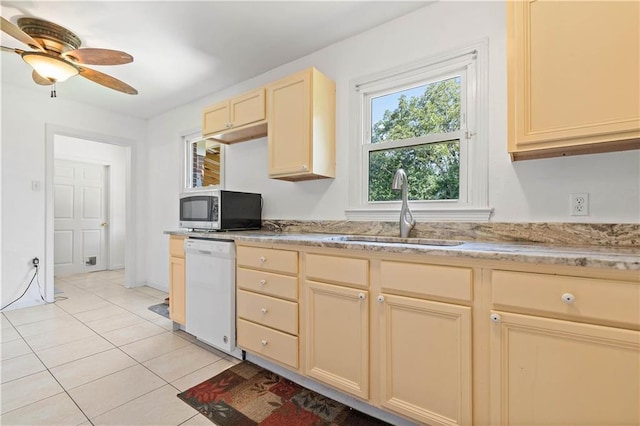 kitchen with stainless steel microwave, white dishwasher, light countertops, a sink, and light tile patterned flooring