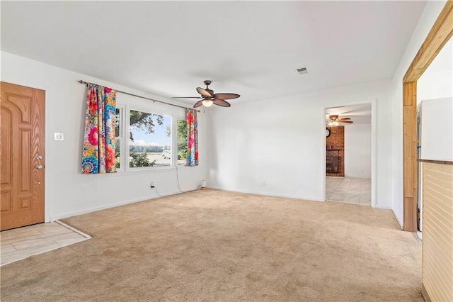 unfurnished living room with light colored carpet, a fireplace, visible vents, and ceiling fan