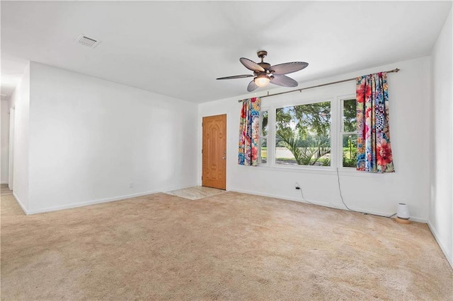 unfurnished room with baseboards, a ceiling fan, visible vents, and light colored carpet