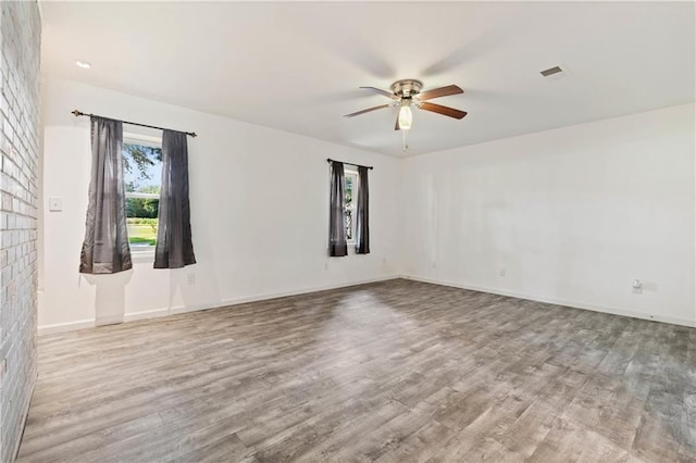 empty room featuring light wood-style floors, visible vents, ceiling fan, and baseboards