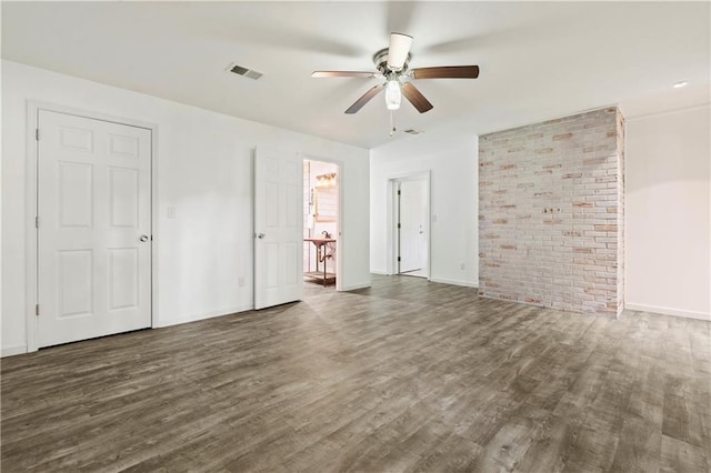 unfurnished bedroom featuring dark wood-style floors, brick wall, visible vents, and baseboards