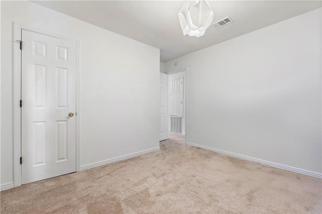 spare room with light colored carpet, visible vents, and baseboards