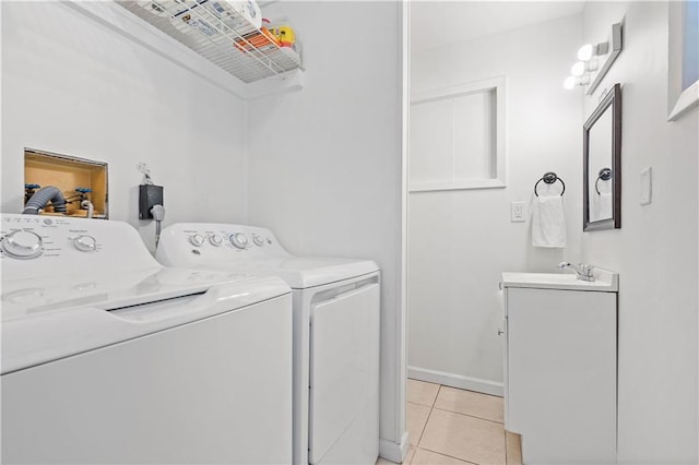 washroom featuring washing machine and dryer, a sink, baseboards, and light tile patterned floors