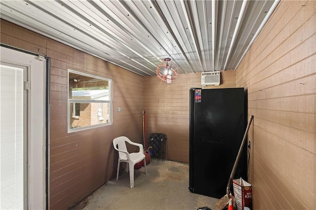 interior space with a wall unit AC, wood walls, and unfinished concrete floors