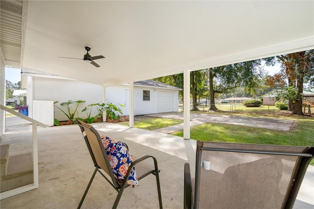 view of patio featuring a garage, ceiling fan, and an outdoor structure