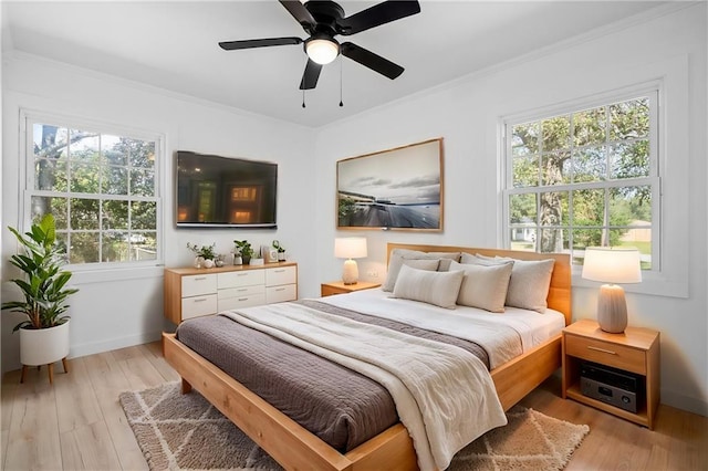 bedroom featuring ceiling fan, light hardwood / wood-style floors, crown molding, and multiple windows