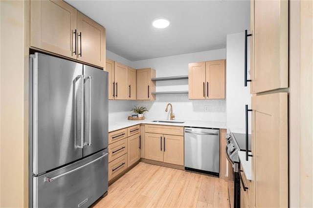 kitchen with sink, light wood-type flooring, light brown cabinets, and appliances with stainless steel finishes