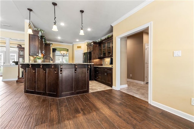 kitchen featuring dark brown cabinets, decorative light fixtures, backsplash, decorative columns, and hardwood / wood-style flooring