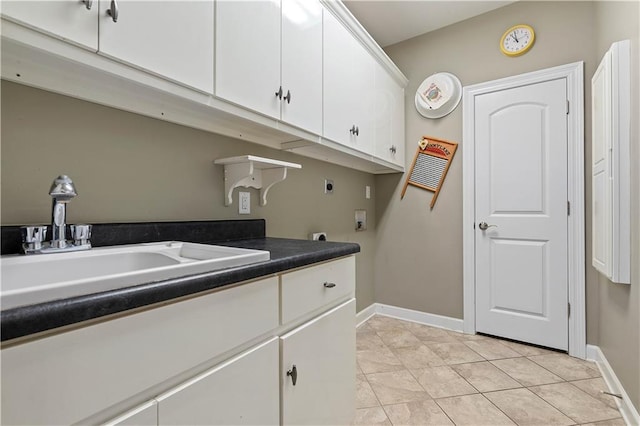 laundry area with electric dryer hookup, cabinets, light tile floors, and sink