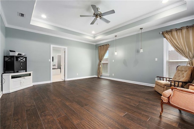 living room featuring a healthy amount of sunlight, ceiling fan, a raised ceiling, and dark wood-type flooring