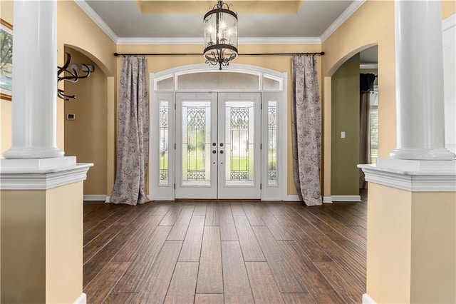 foyer entrance with ornamental molding, dark hardwood / wood-style flooring, a notable chandelier, and a raised ceiling