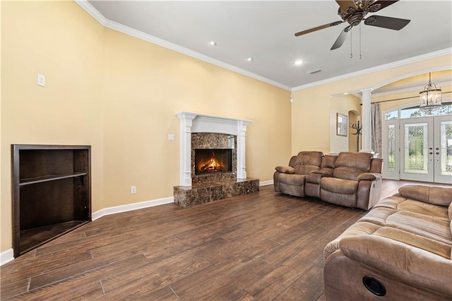 living room featuring wood-type flooring, a fireplace, ceiling fan, and crown molding