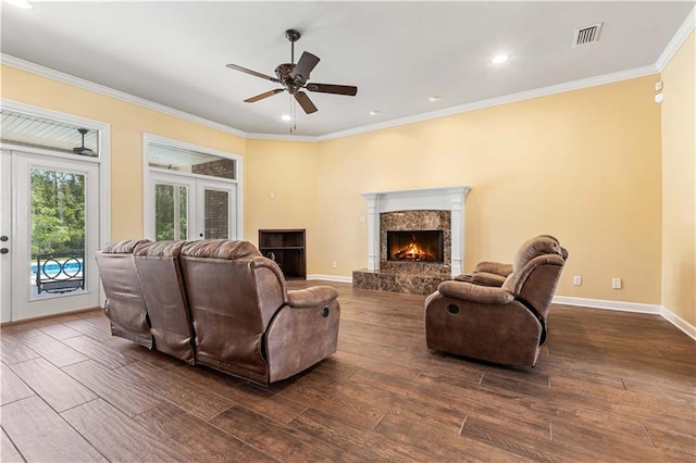 living room with a premium fireplace, crown molding, dark wood-type flooring, and ceiling fan