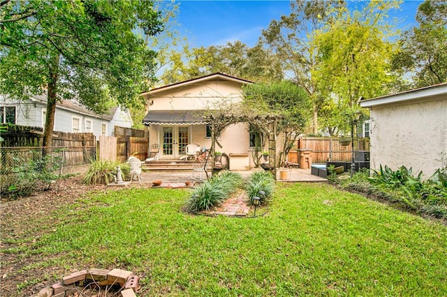 back of property with french doors, a yard, and a patio area