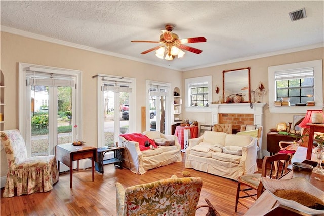 living room featuring ceiling fan, a healthy amount of sunlight, a textured ceiling, and light hardwood / wood-style floors