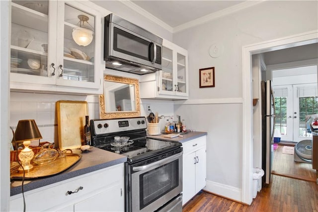 kitchen with white cabinets, dark hardwood / wood-style flooring, ornamental molding, and appliances with stainless steel finishes