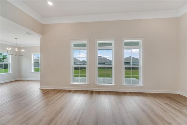 empty room featuring baseboards, an inviting chandelier, ornamental molding, and light wood-style floors