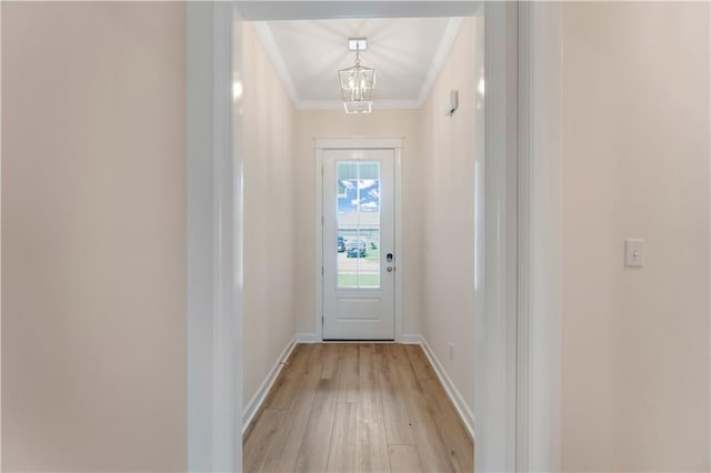 entryway featuring crown molding, baseboards, a notable chandelier, and light wood-style flooring