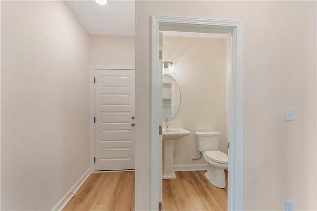 bathroom featuring toilet, baseboards, and wood finished floors