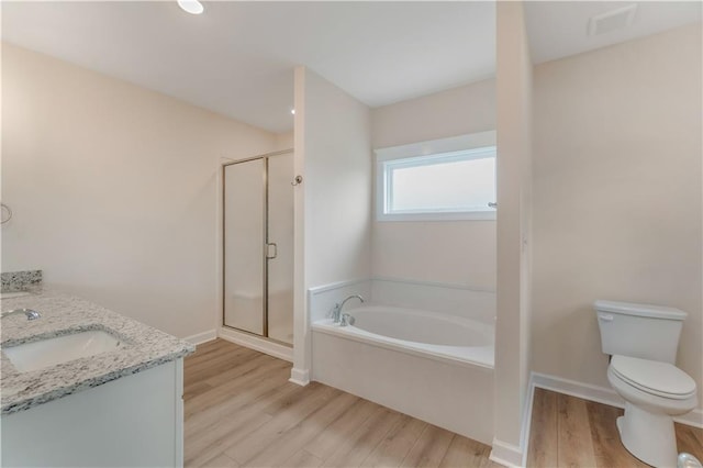 bathroom with a sink, toilet, wood finished floors, a bath, and a stall shower