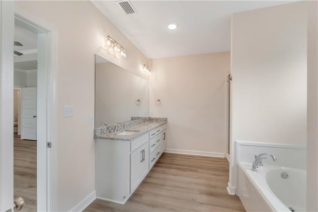 full bath featuring baseboards, a garden tub, wood finished floors, and visible vents