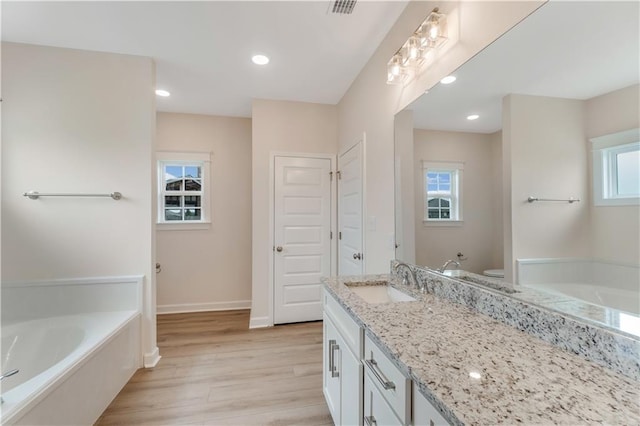 full bath with a bath, wood finished floors, vanity, baseboards, and toilet
