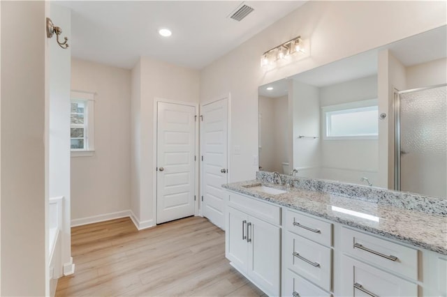 full bath with visible vents, vanity, wood finished floors, baseboards, and a stall shower