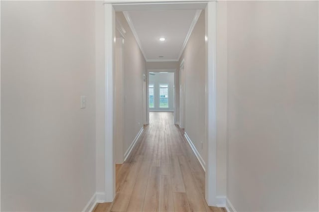 hall with baseboards, ornamental molding, and light wood-type flooring