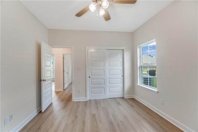 unfurnished bedroom featuring a closet, baseboards, a ceiling fan, and light wood-style floors