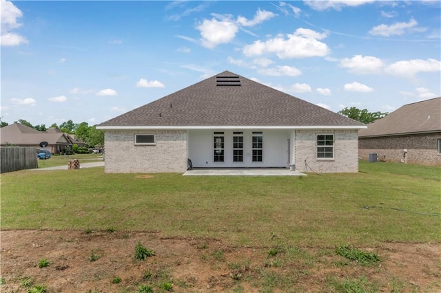 rear view of house with french doors, a lawn, a patio area, and brick siding
