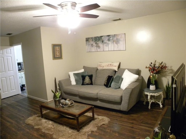 living room featuring ceiling fan, dark hardwood / wood-style flooring, and a textured ceiling