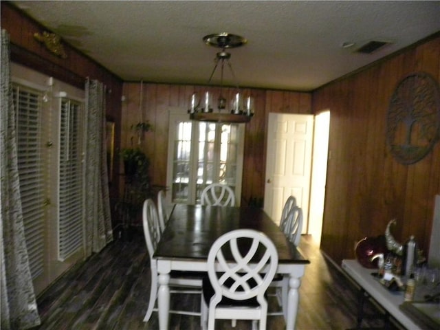 dining area featuring wooden walls, dark wood-type flooring, and a textured ceiling