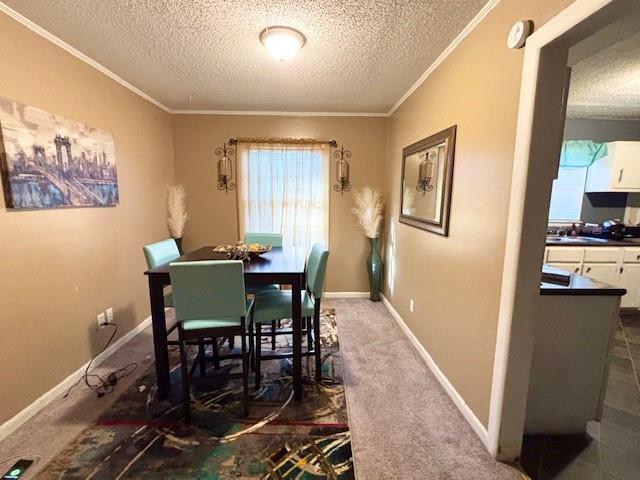 carpeted dining area with sink, a textured ceiling, and ornamental molding