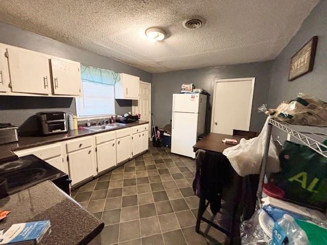 kitchen with black range with electric stovetop, white cabinetry, sink, white refrigerator, and a textured ceiling