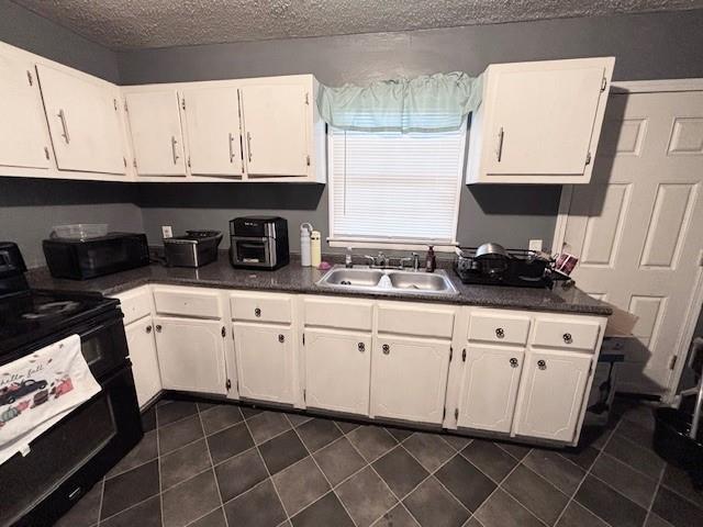 kitchen with sink, white cabinets, black appliances, and a textured ceiling