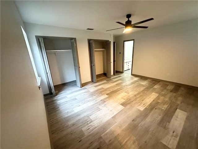 unfurnished bedroom with multiple closets, light wood-type flooring, and ceiling fan