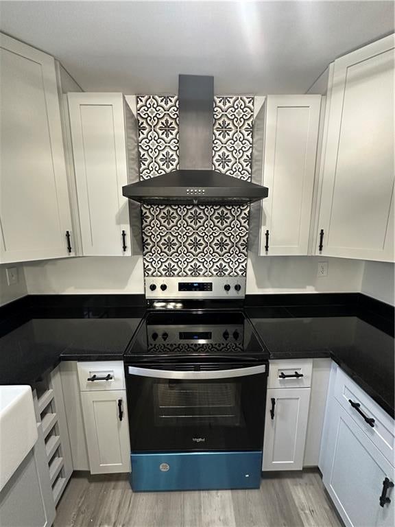 kitchen with white cabinets, light hardwood / wood-style flooring, electric stove, wall chimney exhaust hood, and decorative backsplash