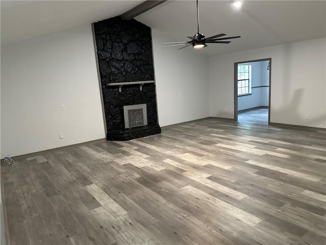 unfurnished living room featuring ceiling fan, lofted ceiling with beams, light wood-type flooring, and a fireplace