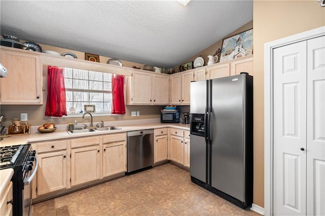 kitchen featuring sink, vaulted ceiling, light brown cabinets, and appliances with stainless steel finishes