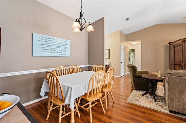 dining area featuring an inviting chandelier, dark wood-type flooring, and vaulted ceiling