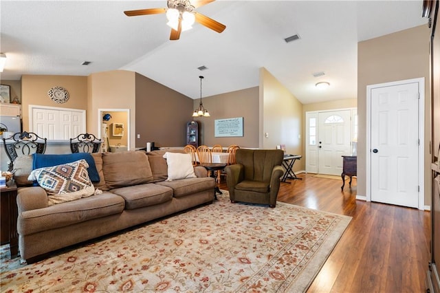 living room with lofted ceiling, ceiling fan with notable chandelier, and dark hardwood / wood-style flooring