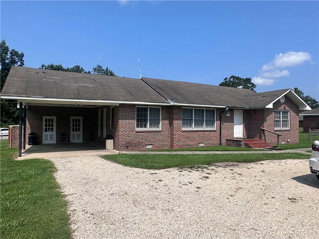 ranch-style home with an attached carport, crawl space, gravel driveway, a front yard, and brick siding