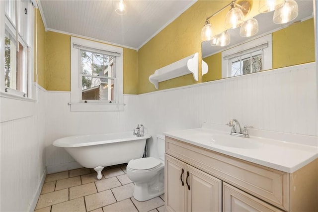 bathroom with tile patterned flooring, vanity, toilet, crown molding, and a bath
