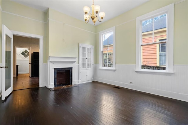 unfurnished living room with dark hardwood / wood-style floors and a notable chandelier