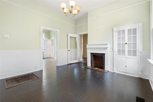 unfurnished living room with an inviting chandelier and dark hardwood / wood-style floors