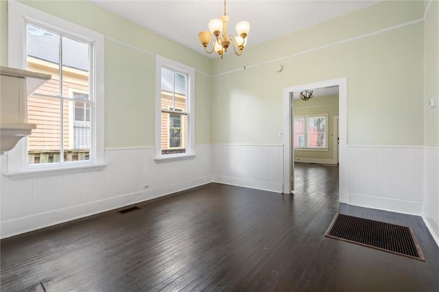 empty room with a notable chandelier and dark hardwood / wood-style flooring