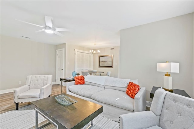 living room featuring ceiling fan with notable chandelier and light hardwood / wood-style floors