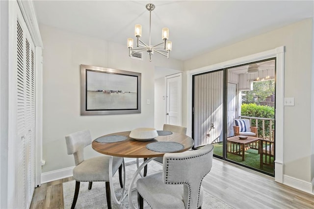 dining area with light hardwood / wood-style floors and a chandelier