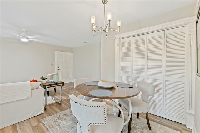 dining room with ceiling fan with notable chandelier and light hardwood / wood-style flooring